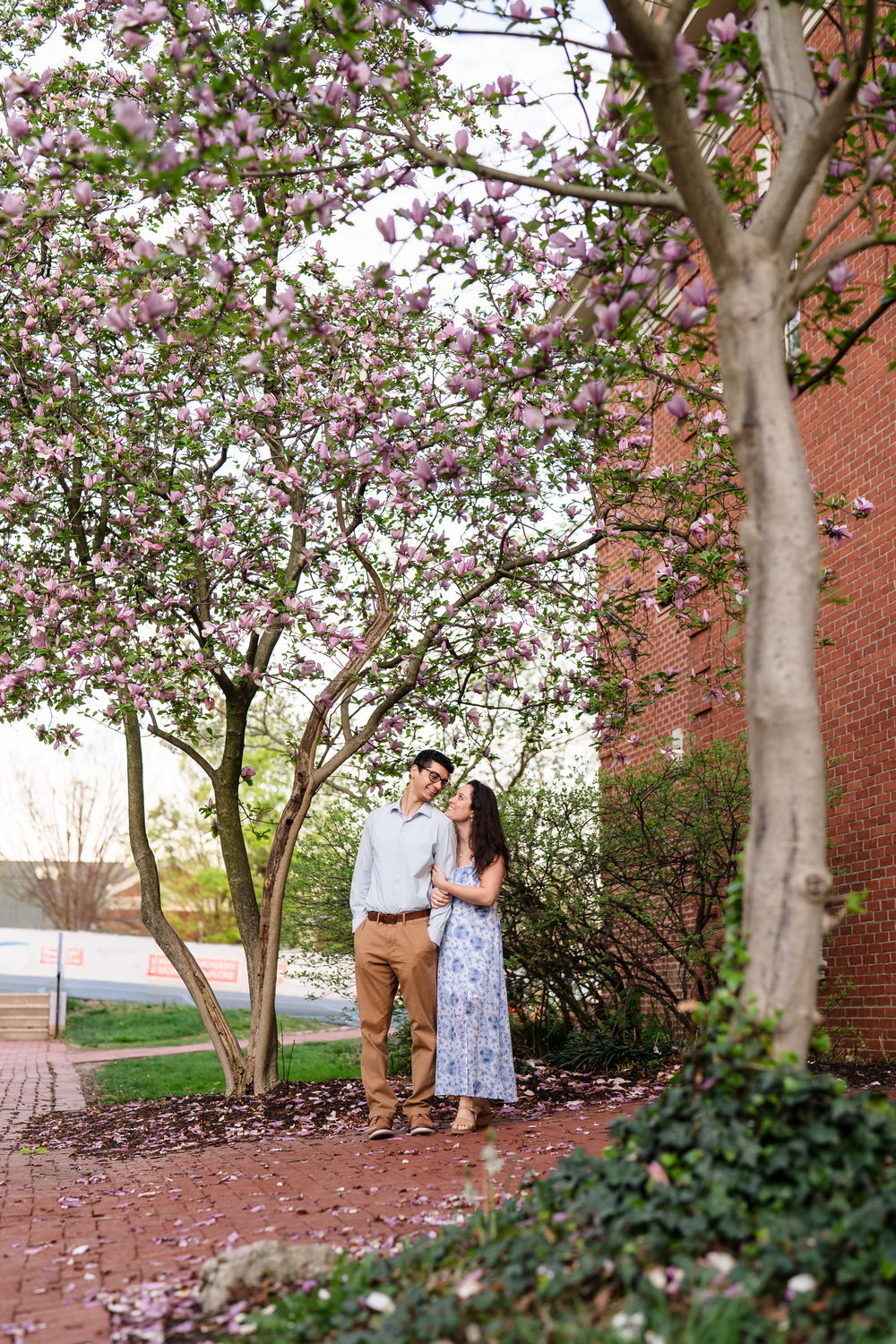Couple embraces beneath full spring trees at Moravian University
