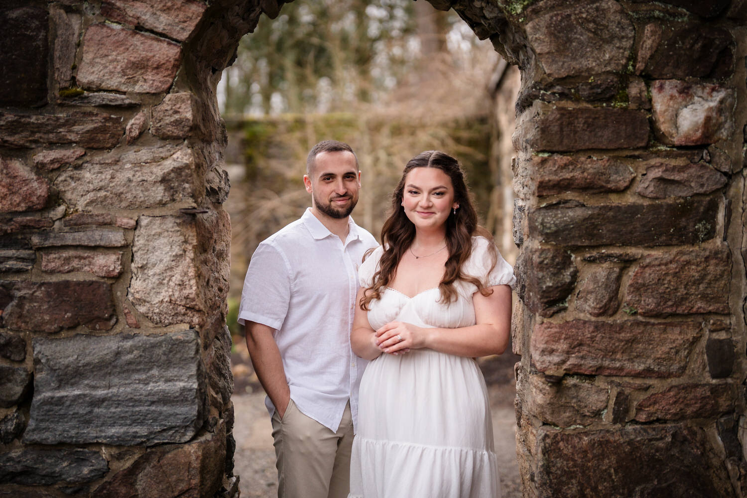 Formal engagement portrait of couple framed by rustic stone archway