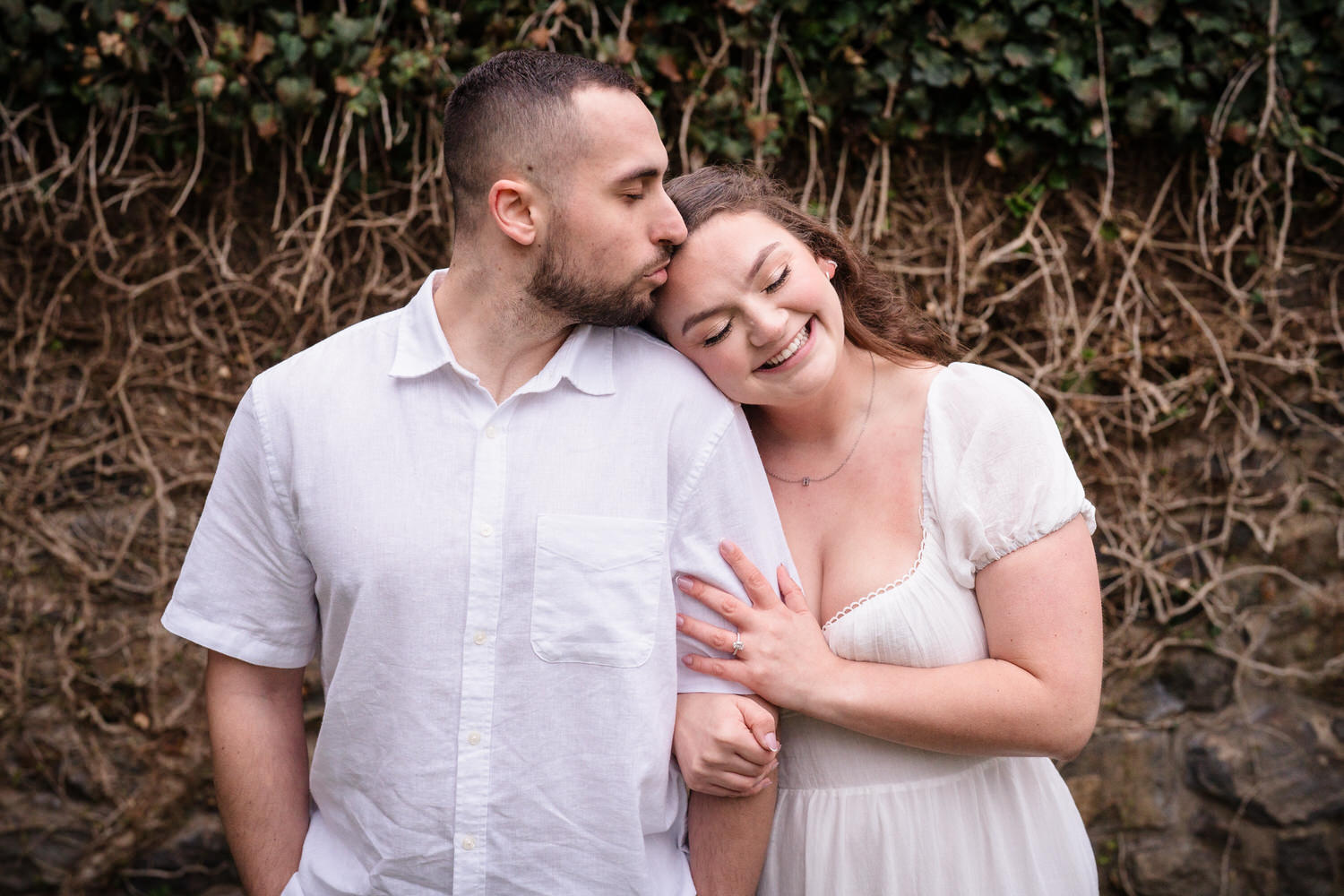 Candid engagement photo of couple smiling and leaning together outdoors