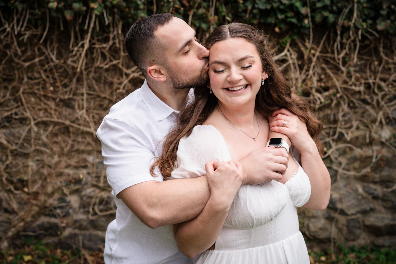 Groom kissing bride’s cheek during joyful engagement session close-up
