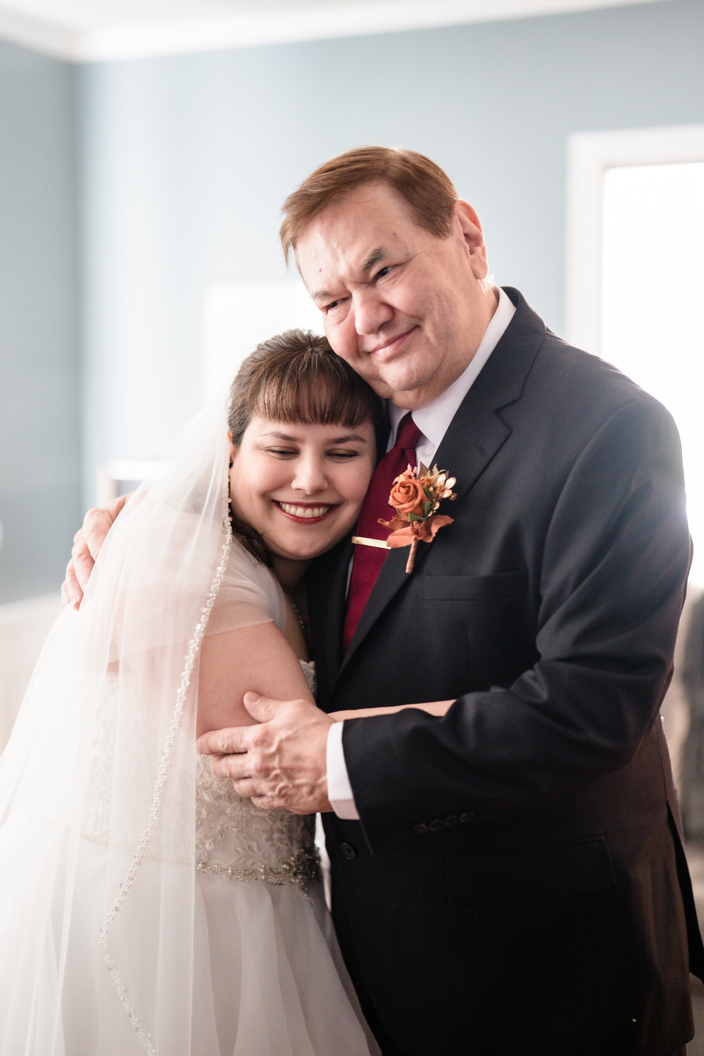 Bride hugging older man during family portraits on wedding day
