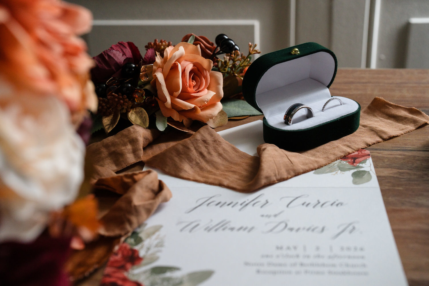 Wedding invitation flat lay with rings, flowers, and elegant details