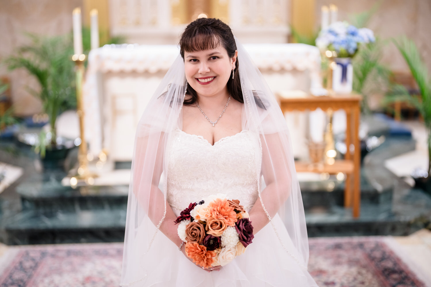 Bride portrait holding orange and burgundy bouquet inside church