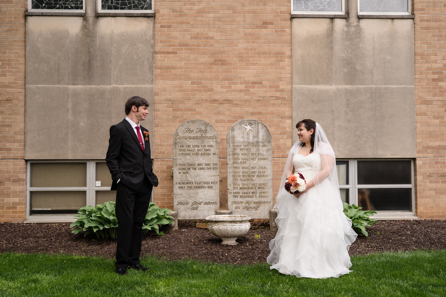 Bride and groom standing near stone plaques outside church
