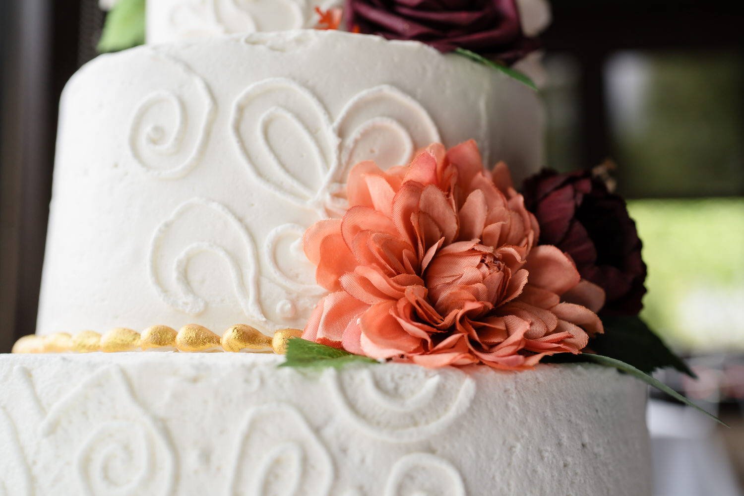 White wedding cake detail with textured icing and orange flower