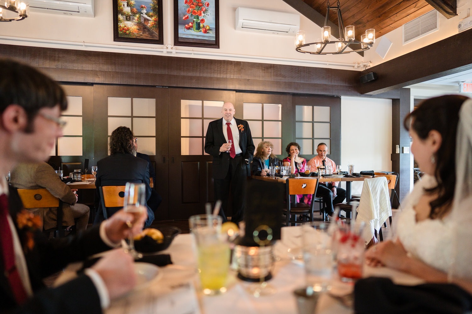 Wedding reception toast with guests seated at decorated tables