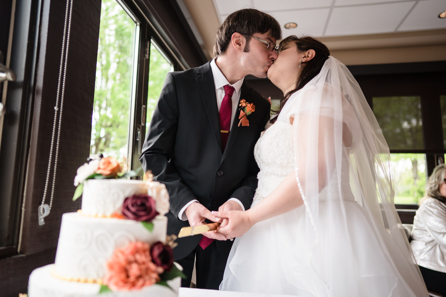 Bride and groom cutting wedding cake together indoors