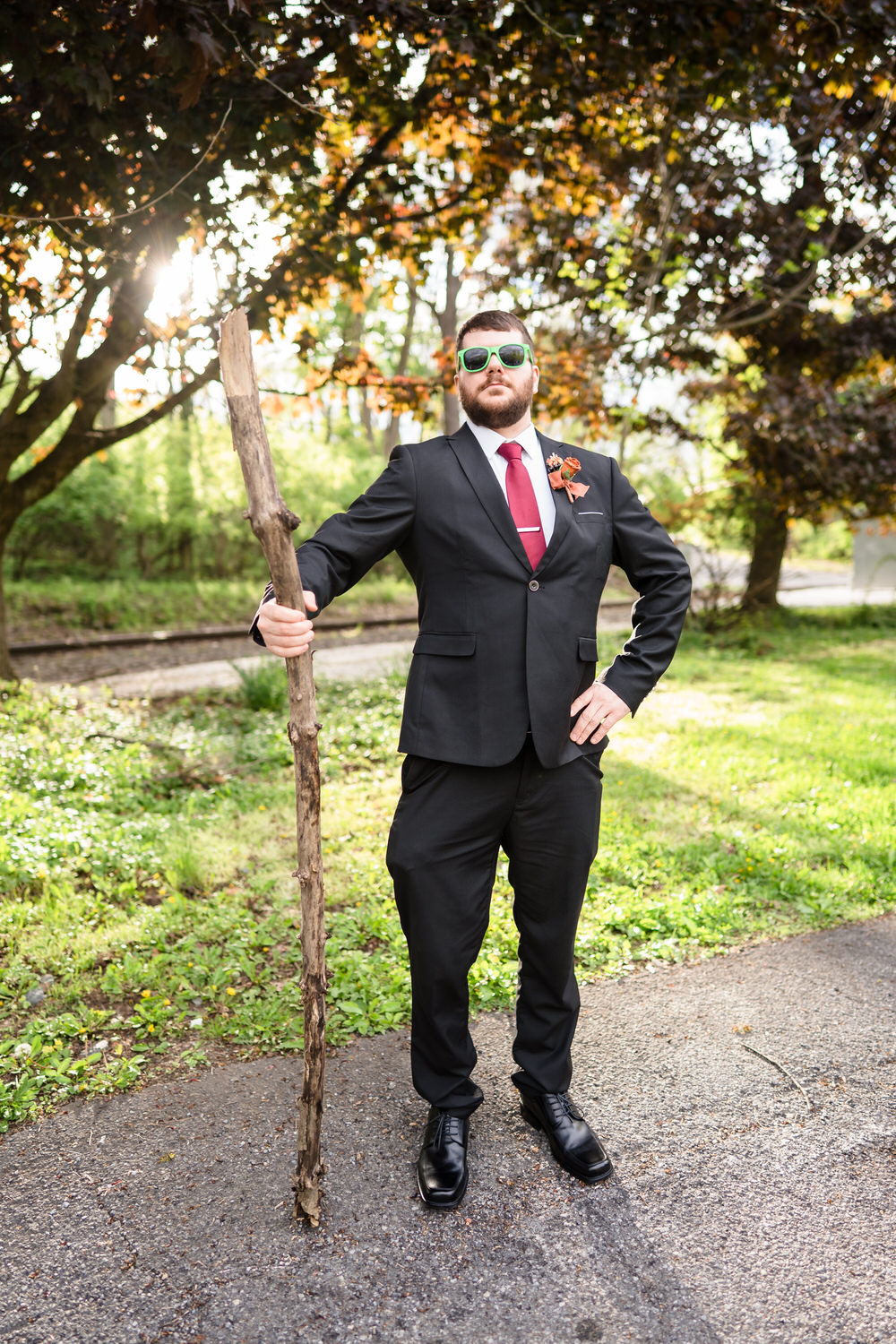 Groom portrait outdoors wearing sunglasses and boutonniere