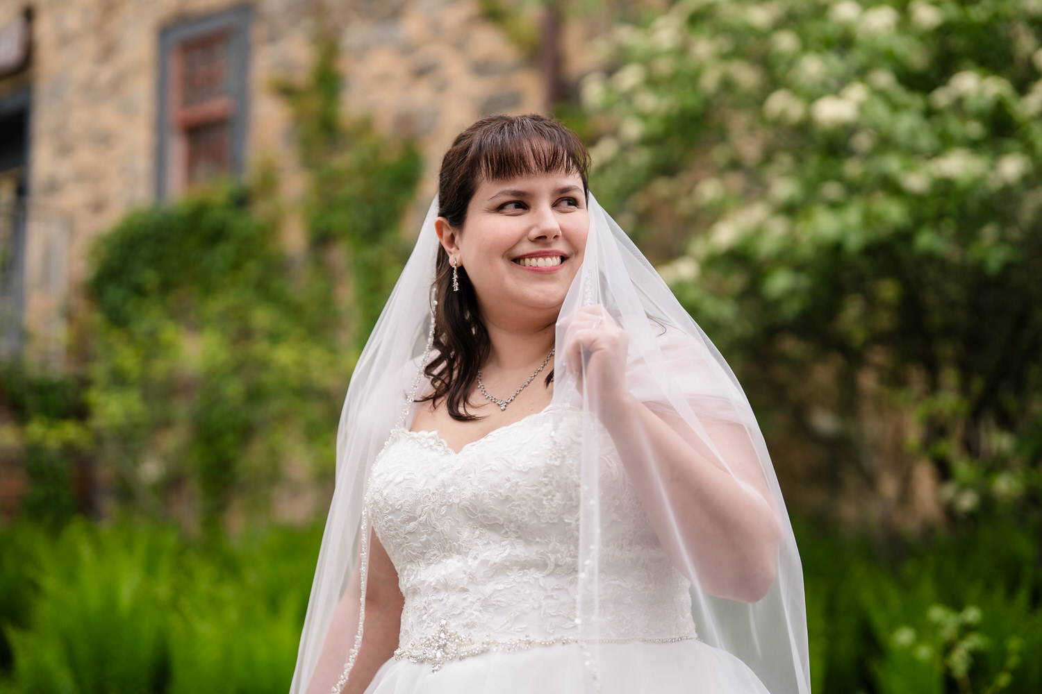 Bride portrait outdoors wearing lace wedding dress and veil