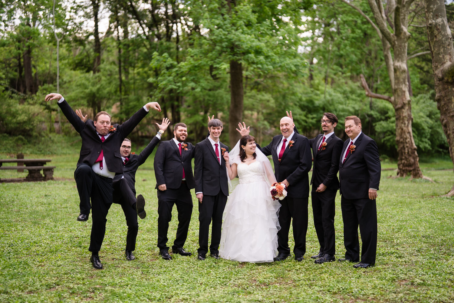 Joyful wedding party cheering around bride and groom outdoors