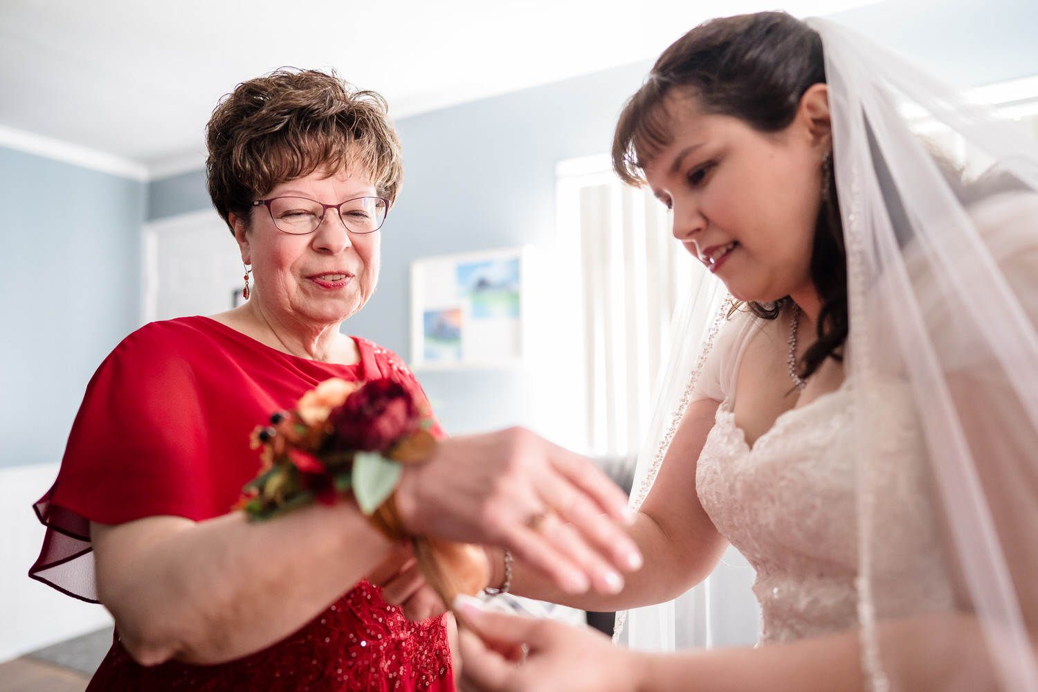 Older woman helping bride put on wedding bracelet before ceremony