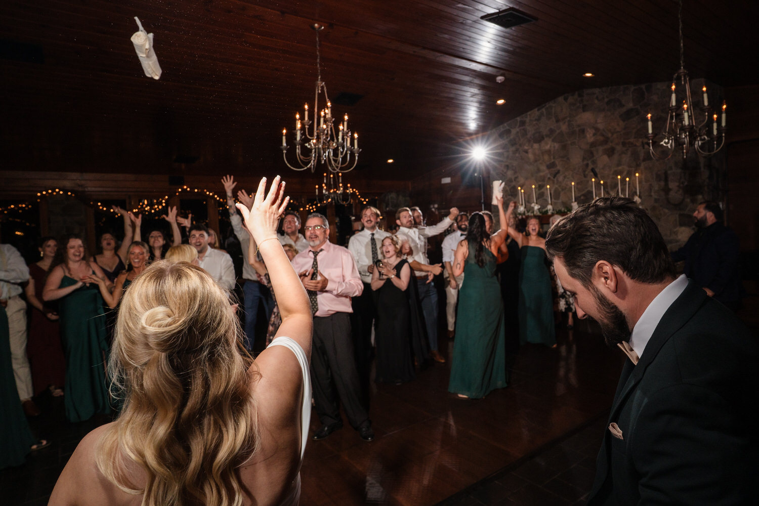 A bride throws her bouquet over her shoulder while guests watch on a dance floor.